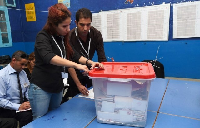 Tunisian election officials open a ballot box in a polling station front of observers during the country's first post-revolution parliamentary election in Tunis on October 26, 2014. Tunisians voted in an election seen as pivotal to establishing democracy in the cradle of the Arab Spring uprisings, with security forces deployed heavily to avert extremist attacks. AFP PHOTO / FADEL SENNA