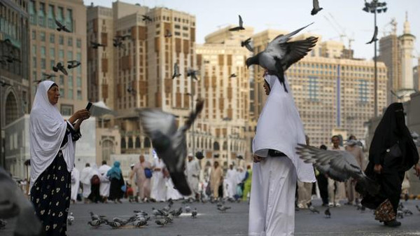 Muslim pilgrims take pictures while standing amongst pigeons outside the Grand mosque in the holy city of Mecca ahead of the annual haj pilgrimage