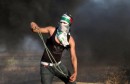 Masked Palestinian protester uses a sling to throw stones at Israeli troops during clashes near the border between Israel and Central Gaza Strip