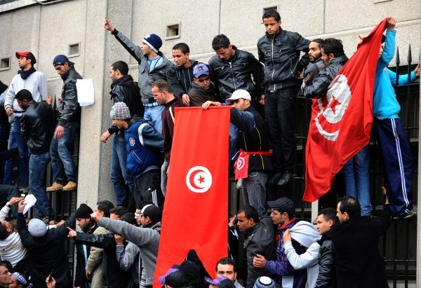 Tunisian demonstrators stand upon railin