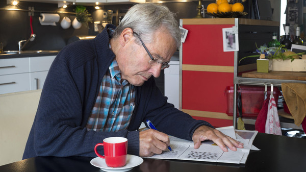 Elderly man solving puzzle in newspaper