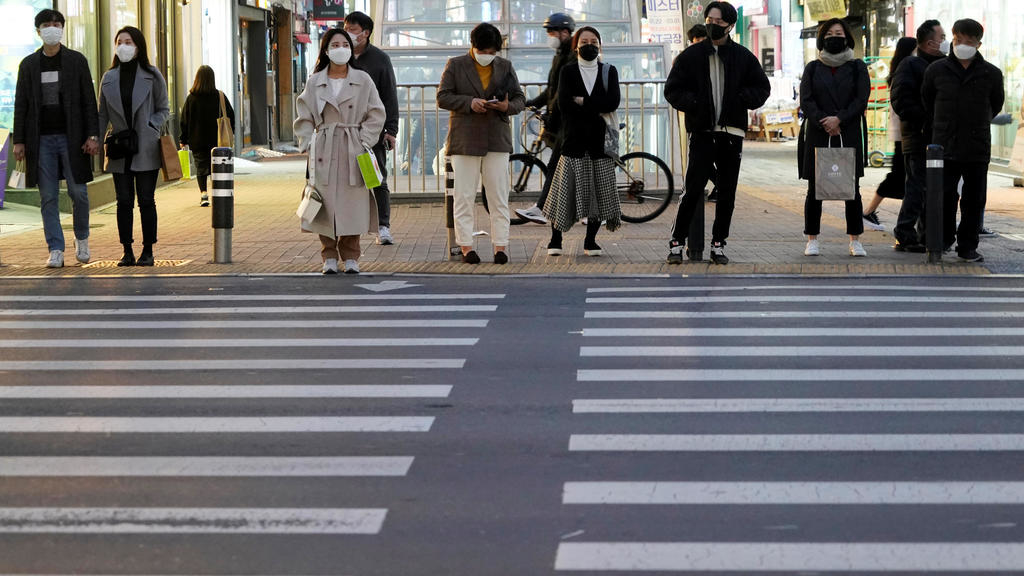 People wearing masks to prevent contracting the coronavirus wait for a signal at a zebra crossing at Dongseong-ro shopping street in central Daegu